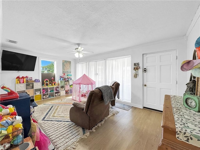 living room with a ceiling fan, visible vents, a textured ceiling, and wood finished floors