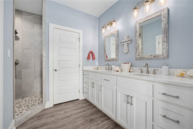 bathroom featuring hardwood / wood-style flooring, vanity, and a tile shower