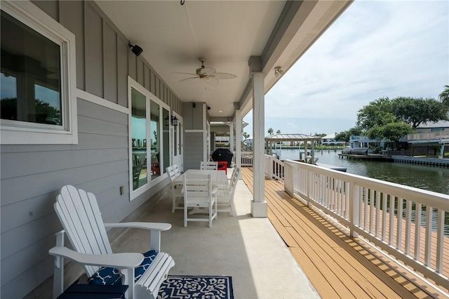 balcony with a deck with water view and ceiling fan