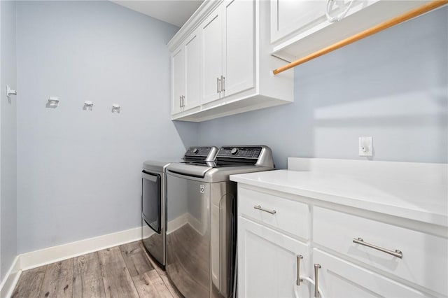 laundry room with cabinets, washer and dryer, and light wood-type flooring