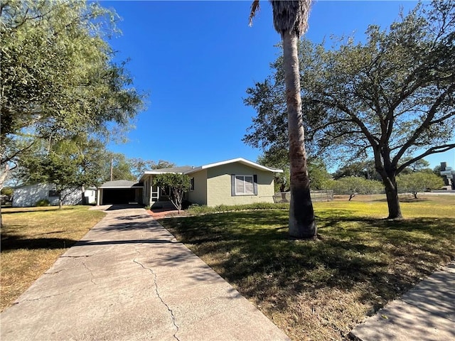 view of front of home featuring concrete driveway, concrete block siding, and a front lawn