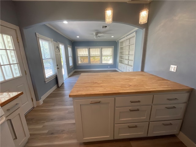 kitchen featuring wooden counters, baseboards, ceiling fan, arched walkways, and white cabinetry