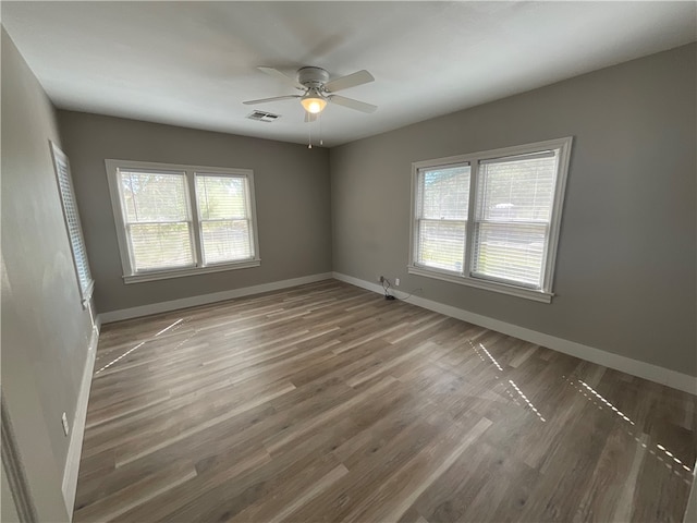 unfurnished room featuring visible vents, baseboards, a ceiling fan, and wood finished floors