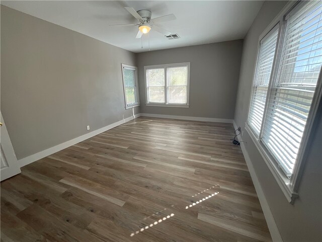 empty room featuring baseboards, wood finished floors, visible vents, and ceiling fan