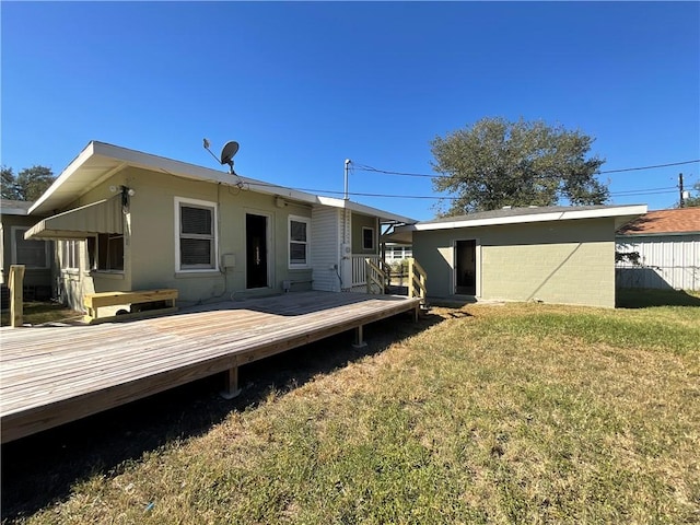 rear view of property with a wooden deck and a lawn