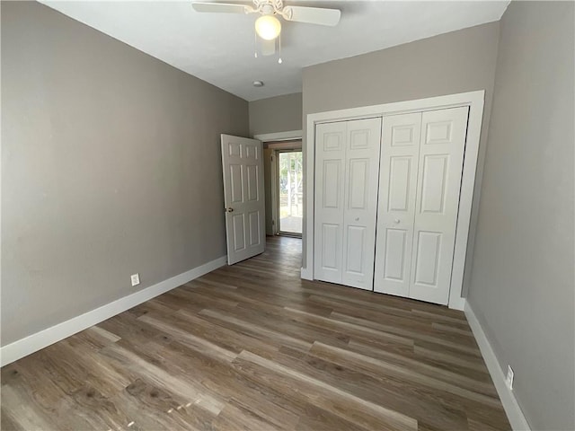 unfurnished bedroom with a closet, baseboards, wood finished floors, and a ceiling fan