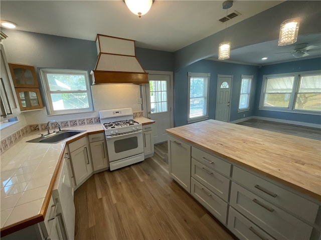 kitchen with visible vents, a sink, wood counters, white appliances, and custom exhaust hood