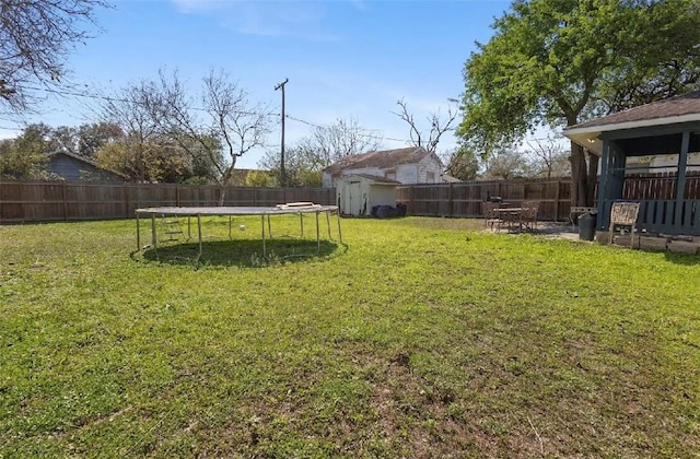 view of yard with a storage shed, a trampoline, an outdoor structure, and a fenced backyard