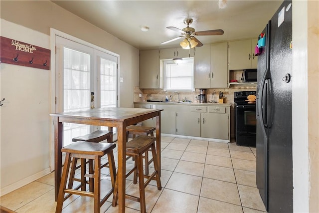 kitchen featuring light tile patterned floors, tasteful backsplash, light countertops, black appliances, and a sink