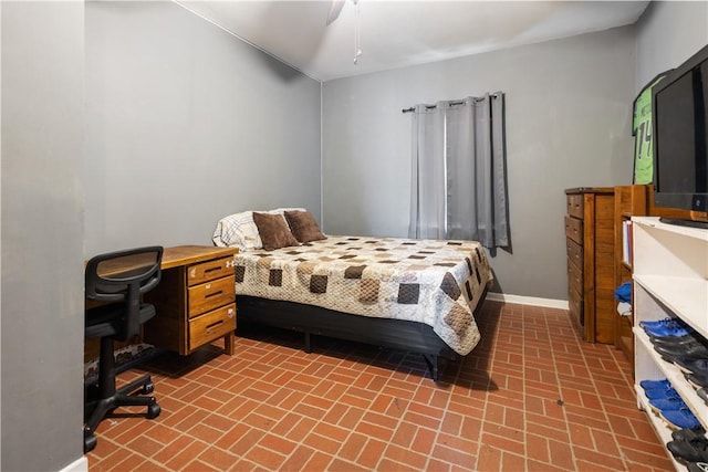bedroom featuring brick floor, a ceiling fan, and baseboards