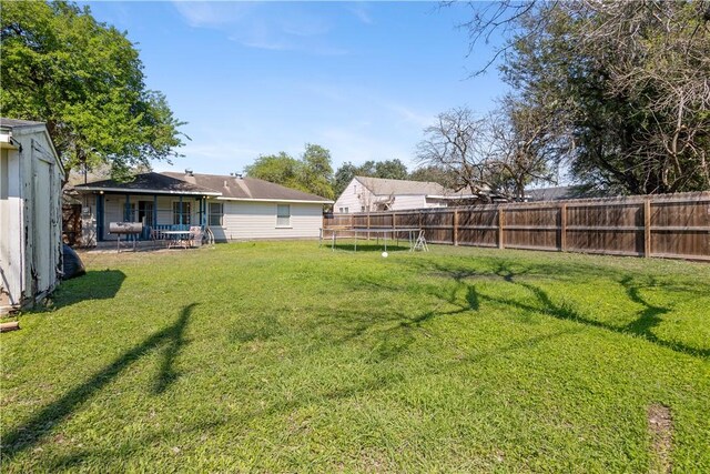 view of yard with a trampoline, a fenced backyard, and a patio