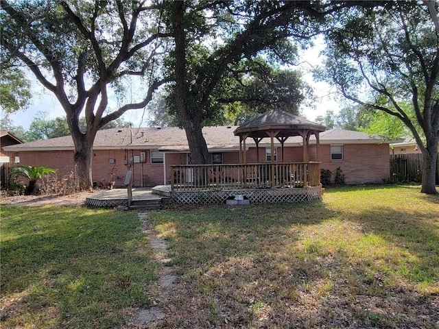 rear view of property with a yard, a gazebo, fence, and brick siding