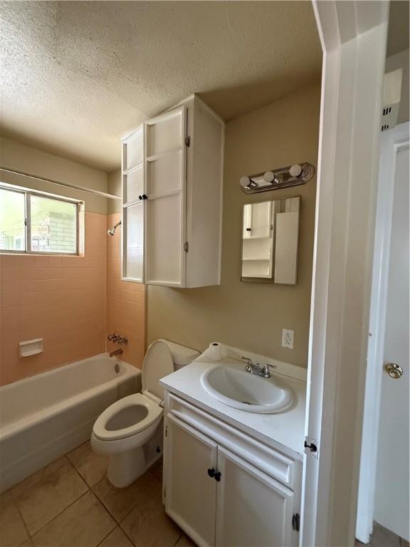 1005 Schallert Dr, Alice, TX 78332 - full bathroom featuring a textured ceiling, tile patterned flooring, vanity, toilet, and bathtub / shower combination