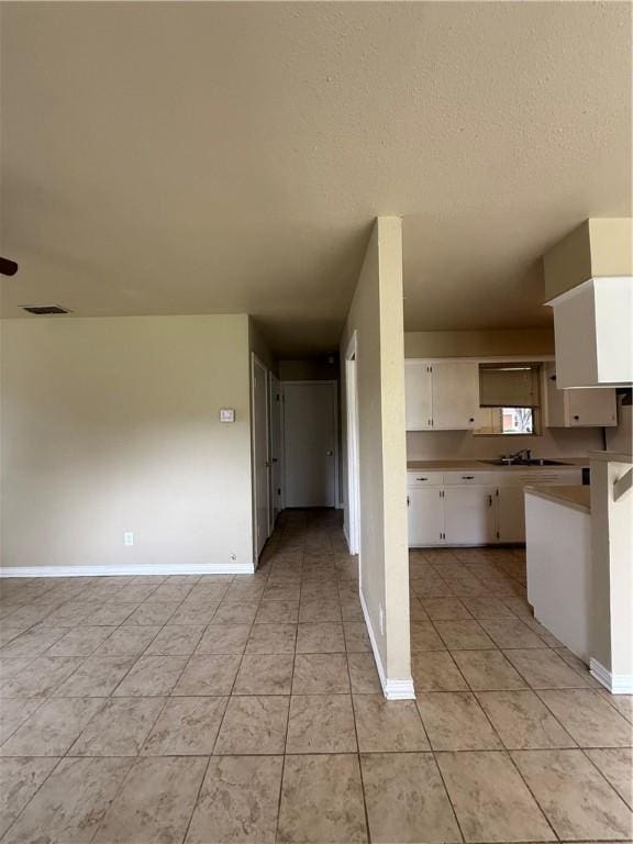 1005 Schallert Dr, Alice, TX 78332 - kitchen featuring white cabinets, baseboards, open floor plan, light tile patterned flooring, and a sink