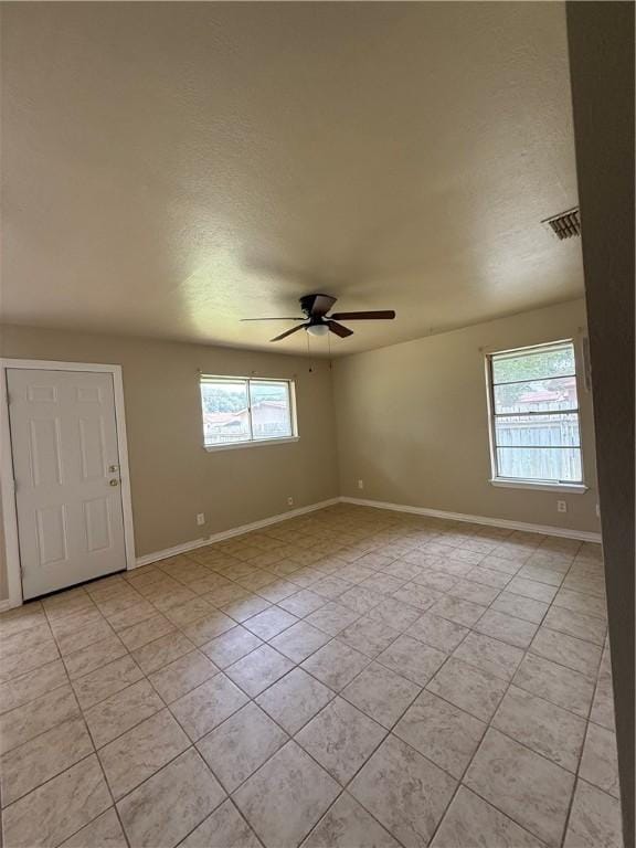 1005 Schallert Dr, Alice, TX 78332 - spare room featuring plenty of natural light, light tile patterned floors, a ceiling fan, baseboards, and a textured ceiling