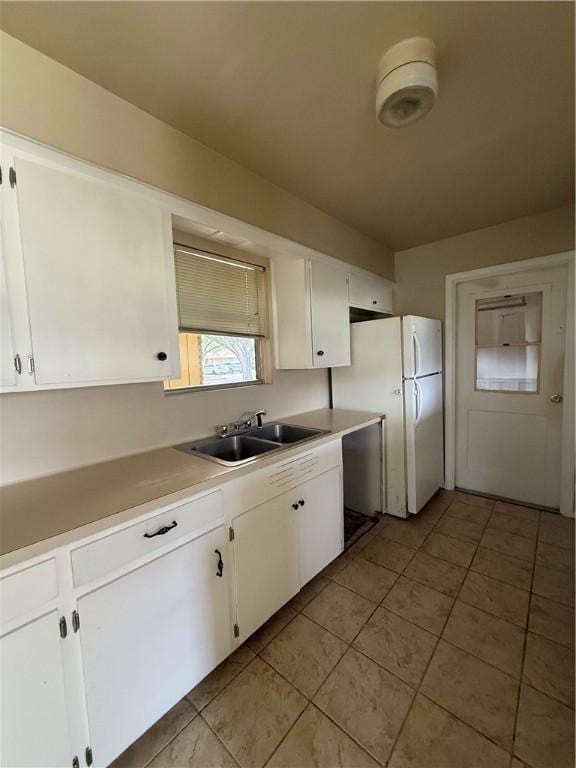 1005 Schallert Dr, Alice, TX 78332 - kitchen featuring a sink, freestanding refrigerator, light tile patterned floors, and white cabinets