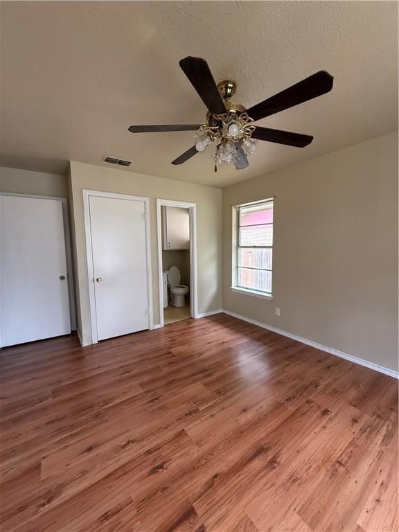1005 Schallert Dr, Alice, TX 78332 - unfurnished bedroom with wood finished floors, baseboards, a ceiling fan, and ensuite bathroom