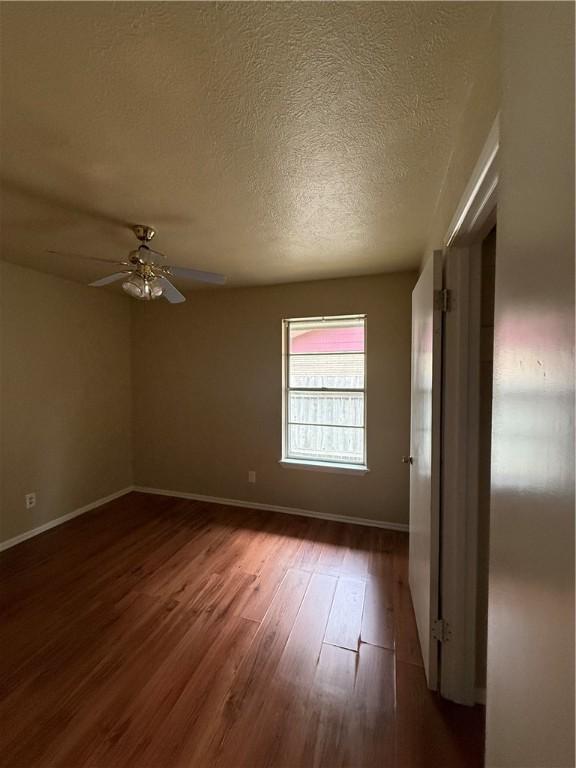 1005 Schallert Dr, Alice, TX 78332 - spare room with dark wood-style floors, baseboards, a ceiling fan, and a textured ceiling