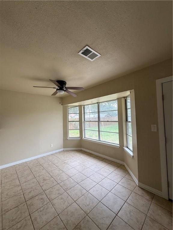 1005 Schallert Dr, Alice, TX 78332 - spare room with light tile patterned floors, a textured ceiling, baseboards, and a ceiling fan