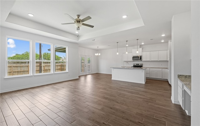 3401 Travis Ct, Corpus Christi, TX 78414 - unfurnished living room featuring a tray ceiling, ceiling fan, recessed lighting, dark wood-style floors, and a chandelier