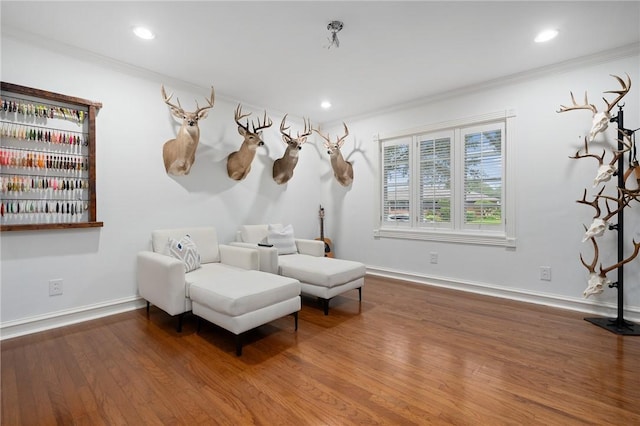 living area featuring wood-type flooring and ornamental molding