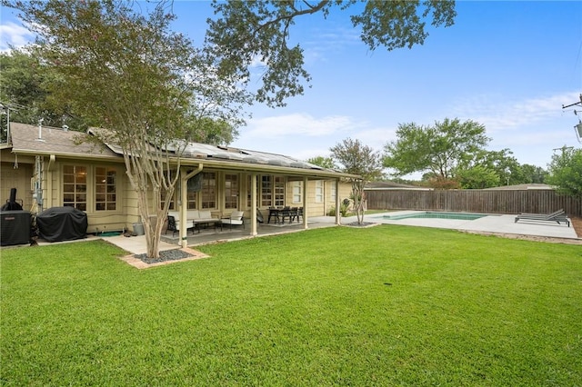 back of house with a fenced in pool, a patio area, a yard, and solar panels