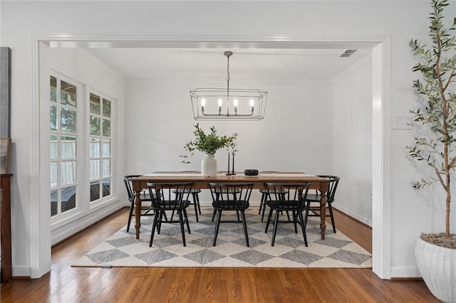 dining room with a notable chandelier, wood-type flooring, and crown molding