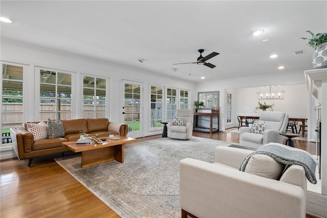 living room featuring ornamental molding, ceiling fan with notable chandelier, and hardwood / wood-style flooring