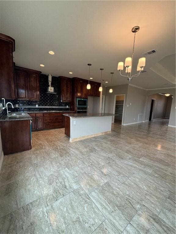 kitchen with visible vents, backsplash, open floor plan, a sink, and extractor fan