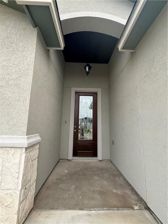 doorway to property featuring stucco siding