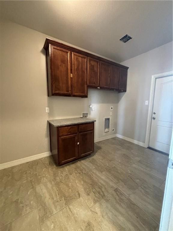 kitchen featuring dark brown cabinets, light countertops, and baseboards