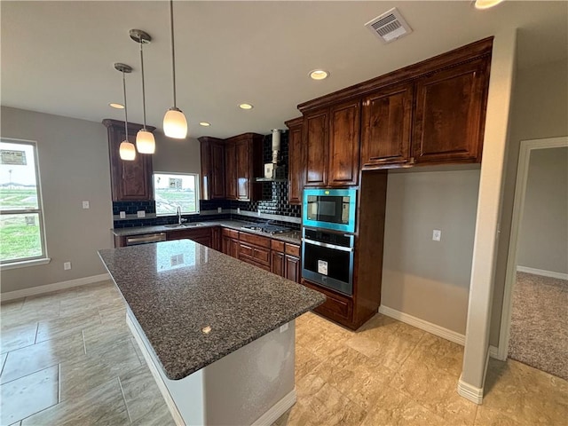 kitchen with stainless steel appliances, visible vents, backsplash, a sink, and dark stone countertops