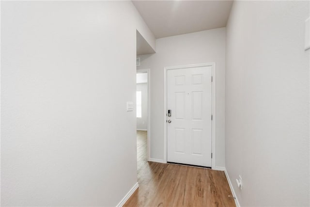 doorway to outside with light wood-style flooring and baseboards