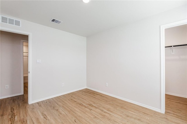 unfurnished bedroom featuring light wood-style flooring, a closet, visible vents, and baseboards