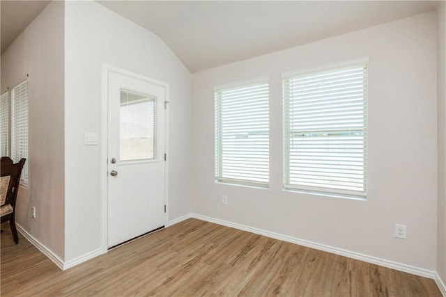 foyer entrance with light wood-style flooring, baseboards, and vaulted ceiling