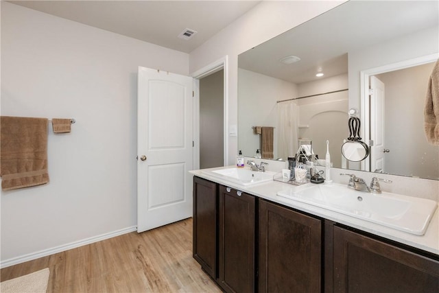 full bath with wood finished floors, a sink, visible vents, and baseboards