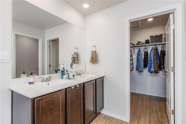 full bath with double vanity, baseboards, a sink, and wood finished floors