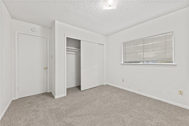 unfurnished bedroom featuring a textured ceiling, light carpet, and a closet