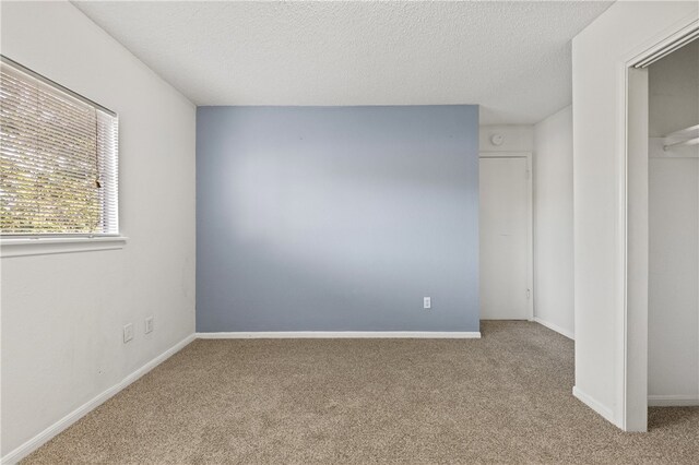 unfurnished bedroom with light colored carpet and a textured ceiling