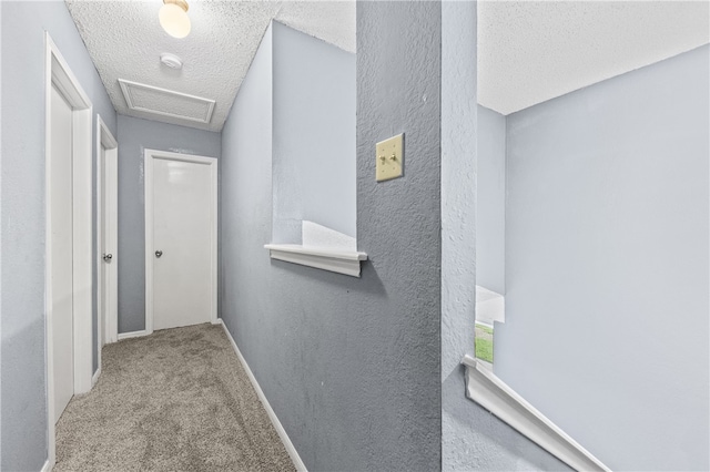 hallway featuring a textured ceiling and light carpet