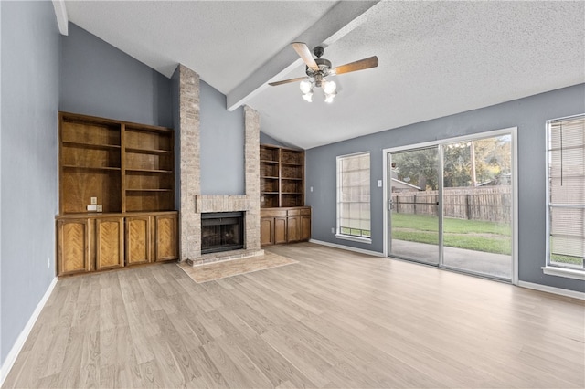 unfurnished living room featuring light hardwood / wood-style floors, vaulted ceiling with beams, a textured ceiling, ceiling fan, and a large fireplace