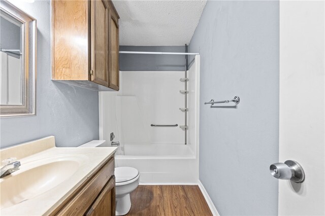 full bathroom with a textured ceiling, hardwood / wood-style floors,  shower combination, vanity, and toilet