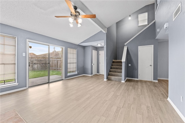 unfurnished living room with a wealth of natural light, a textured ceiling, and light wood-type flooring