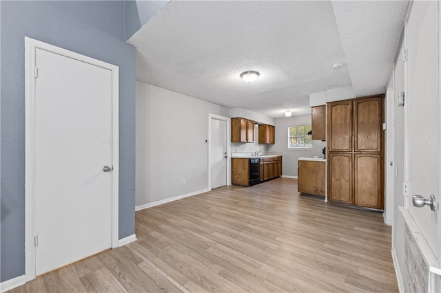 kitchen featuring black dishwasher, light hardwood / wood-style flooring, a textured ceiling, and sink