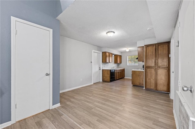 7006 Powderhorn Ct, Corpus Christi, TX 78413 - kitchen with a textured ceiling, light wood-type flooring, brown cabinets, light countertops, and black dishwasher