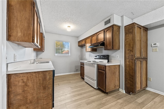 kitchen featuring a textured ceiling, light wood-type flooring, white range, and sink