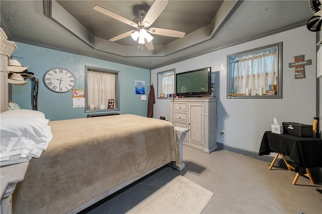 bedroom with a ceiling fan, a tray ceiling, and concrete flooring