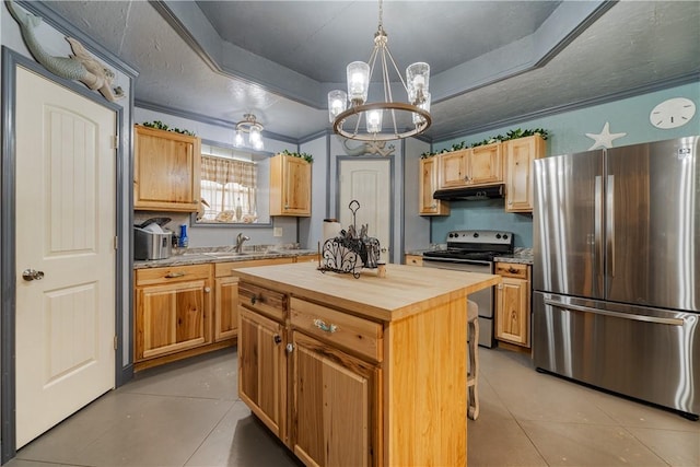 kitchen featuring butcher block counters, a raised ceiling, under cabinet range hood, a chandelier, and appliances with stainless steel finishes