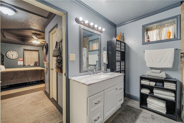 ensuite bathroom featuring connected bathroom, a textured wall, ceiling fan, vanity, and ornamental molding