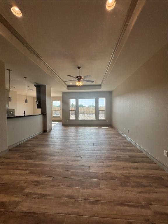 106 Guadalupe Palm Cir, Portland, TX 78374 - unfurnished living room with a tray ceiling, dark wood-type flooring, ceiling fan, and crown molding